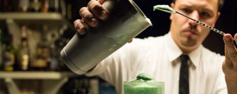 Bartender pours a drink out of a metal shaker at Pepe Le Moko