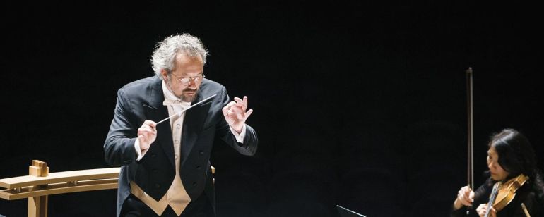 orchestra conductor leading stringed instruments players