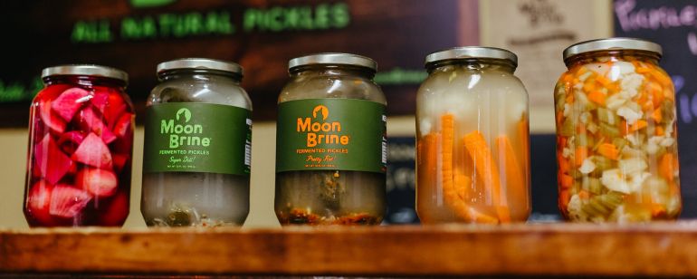 A row of jars of fermented vegetables (including carrots, pickles and beets) from the pickle brand MoonBrine