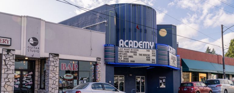 a blue theater with a car parked out front
