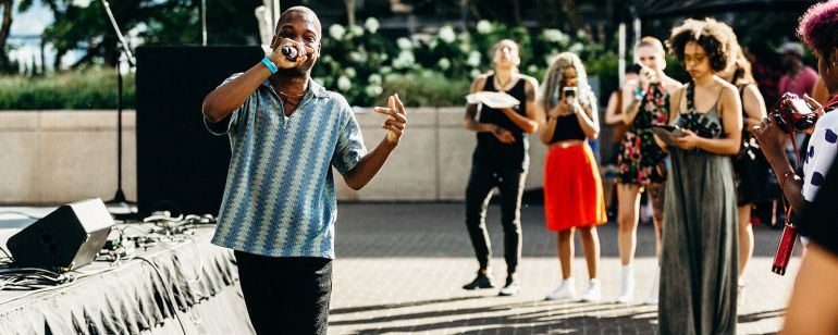 a person sings into a microphone in front of a small crowd