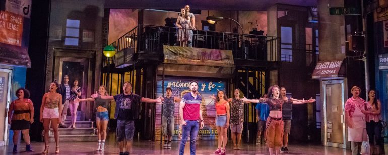the cast of a musical theater show on stage singing during a performance