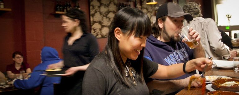 A couple enjoys a meal and beer at a restaurant.