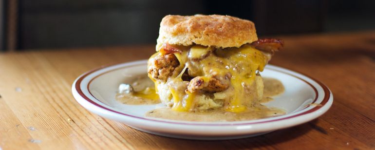 A biscuit sandwich with egg, sausage and melted cheese on a plate