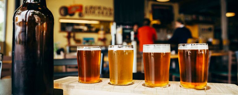 a tasting flight of draft beers next to an open bottle