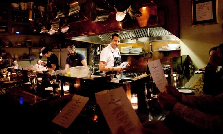 a chef stands in a small open kitchen