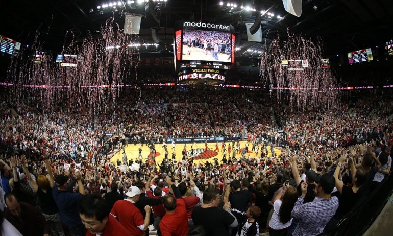 Streamers rain down over a basketball court and thousands of fans