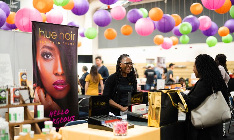 A vendor greets an attendee at My People\'s Market