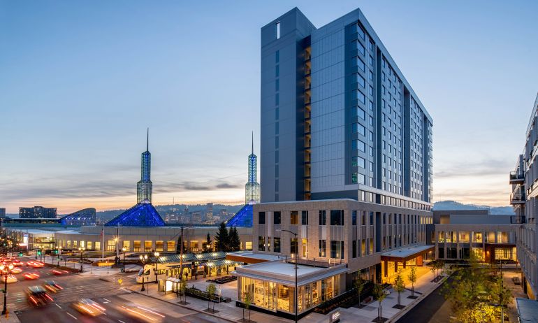 Exterior view of the Hyatt Regency Portland with the twin spires of the Oregon Convention Center in the background