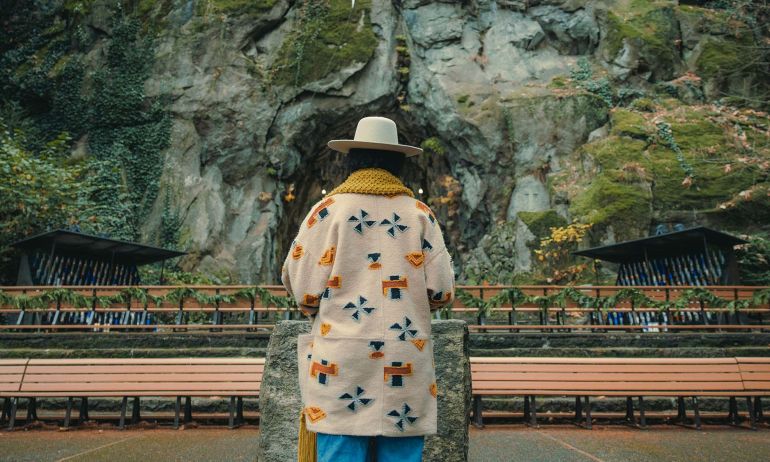 Someone stands in front of a rock wall.