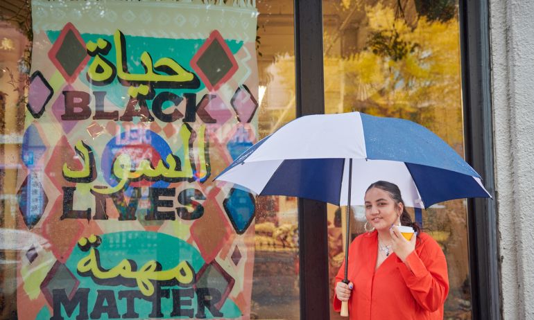 a woman holding an umbrella and coffee cup