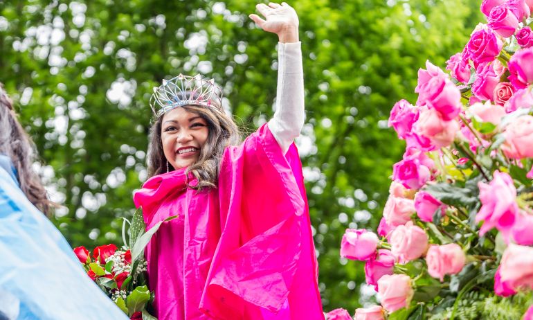 rose festival 2017 rose queen in pink cape with pink roses smiles and waves