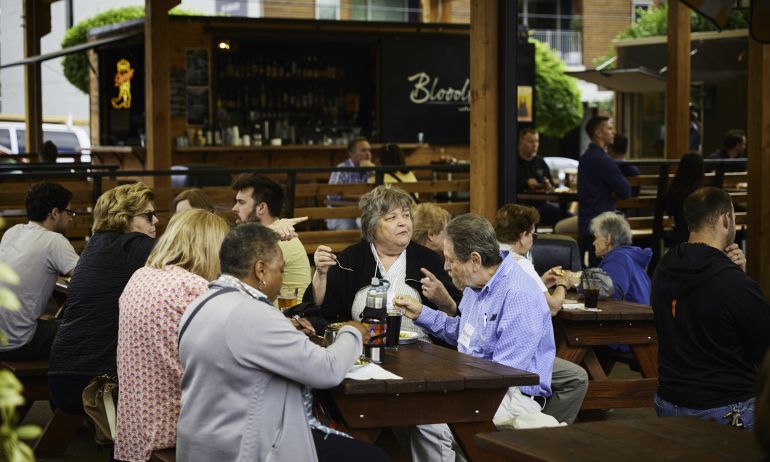 people eating at picnic tables in busy food cart pod