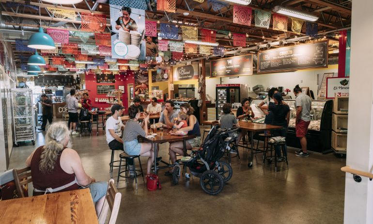 groups of people at tables in an indoor market dining area