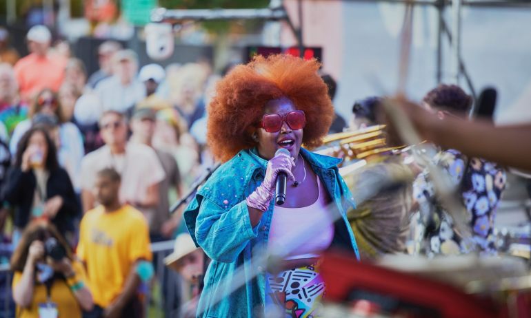 a colorfully-dressed performer sings on stage in front of musicians