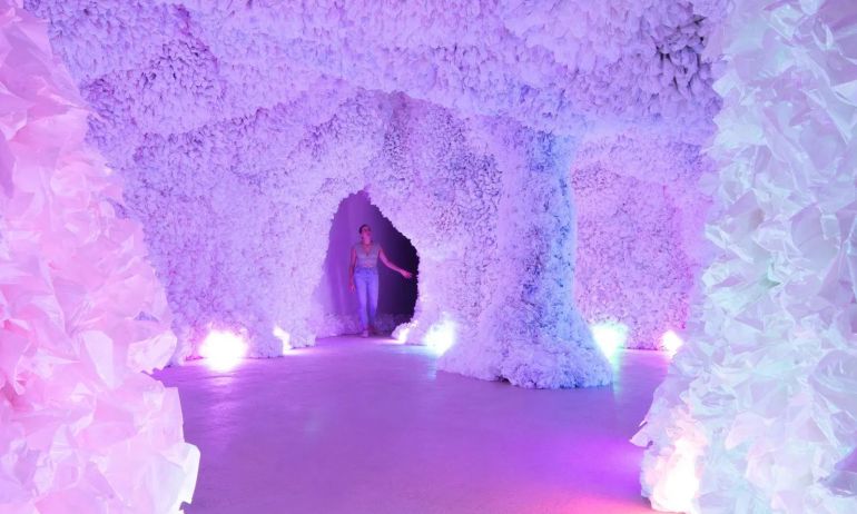 A person explores brightly lit, highly textured cave-like structure.