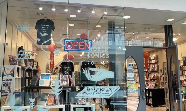 comic book store front showing shelves, books and t-shirts inside