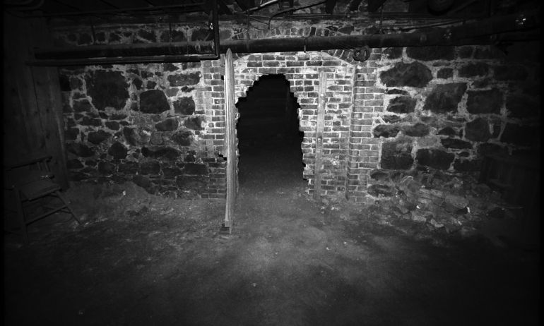 a black and white image of a crumbling doorway in a brick wall