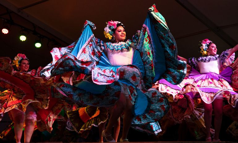 dancers in elaborate dresses on stage during portland\'s cinco de mayo fiesta