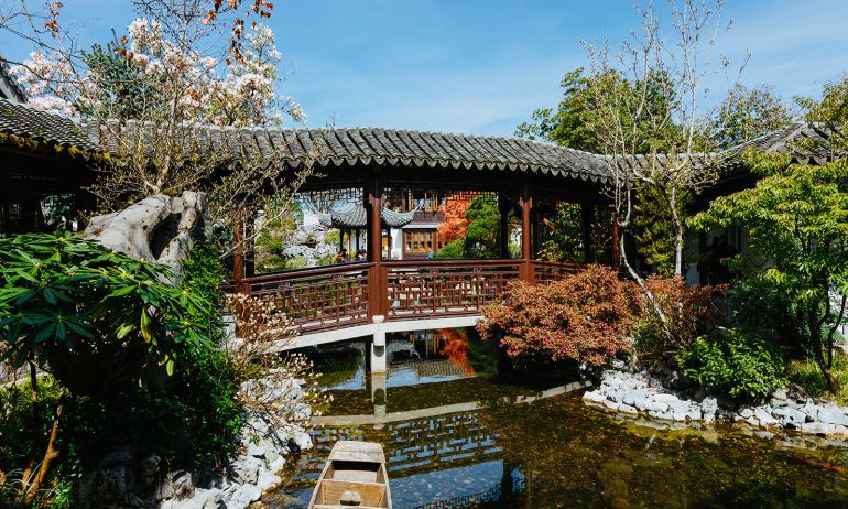 covered bridge crossing a narrow garden stream