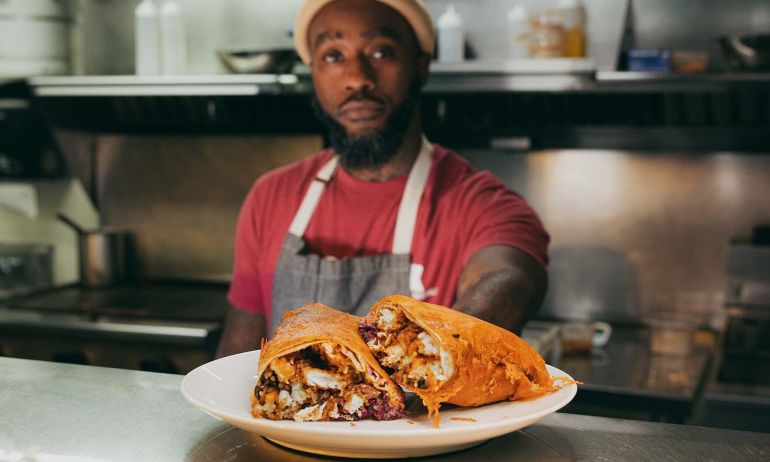 a chef serves a dish with the plate and food in focus