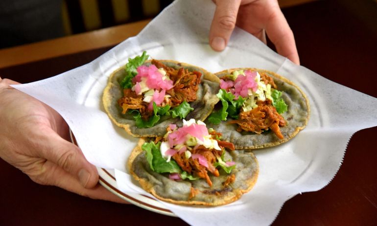 three beautifully made panuchos being held on a plate