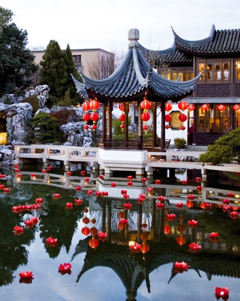 red lanterns float in water in front of a Chinese-style building