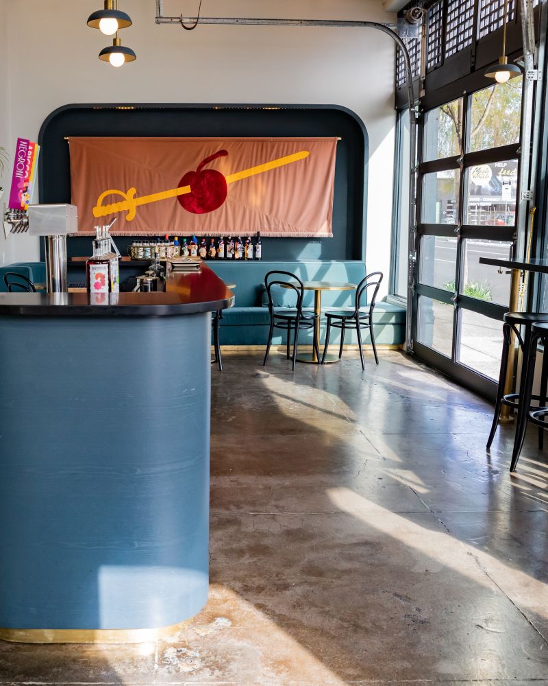 a cocktail tasting room with a bar, stools, a large glass door and colorful decor