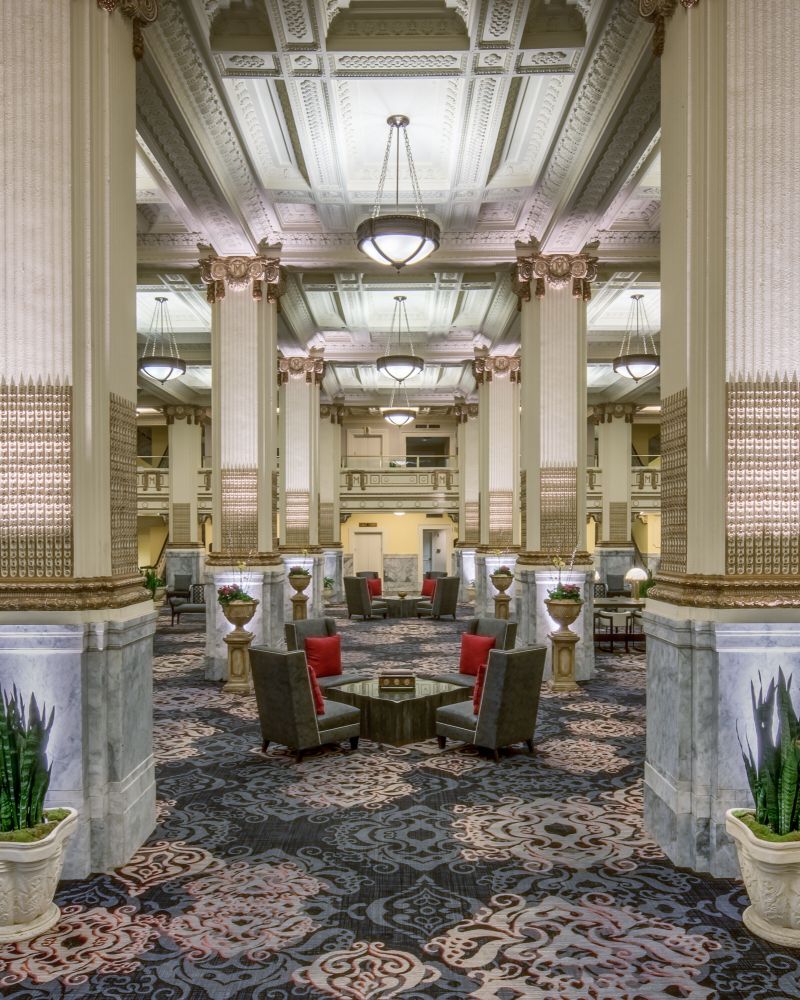 The elegant lobby of the Embassy Suites by Hilton Portland Downtown, complete with marble-based columns and intricate ceiling moldings.