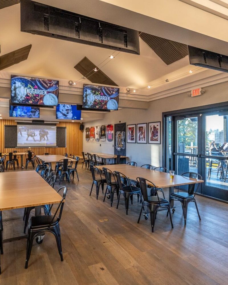 tables and chairs furnish a modern event space under mounted flat-screen TVs