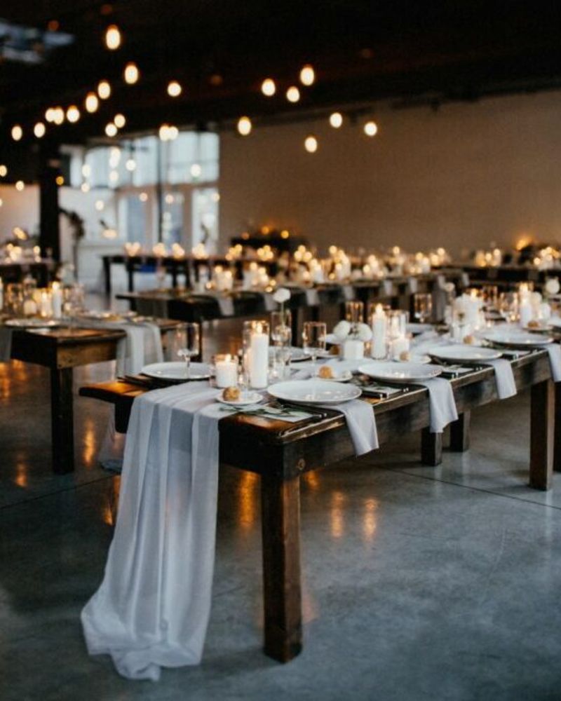 Long dining tables set up for an event at Everett West with flickering candles and draped white table runners.