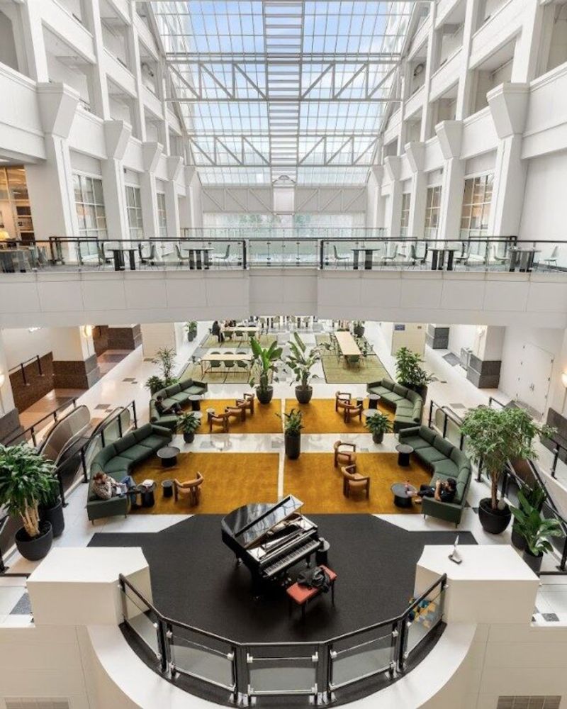 An airy atrium with a black piano in the foreground.