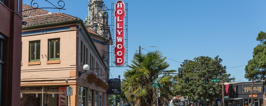 people walking on the sidewalk under a vintage Hollywood Theater sign