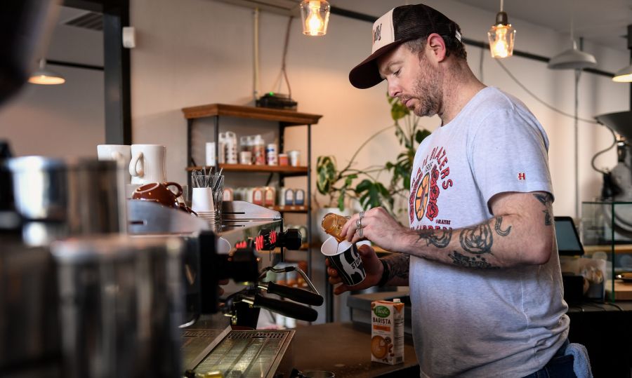 barista pours a shot into a cup behind the bar at a coffee shop