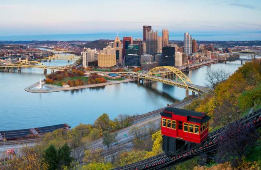 buildings in a city on river bend with many bridges and a bright red mountain side tram