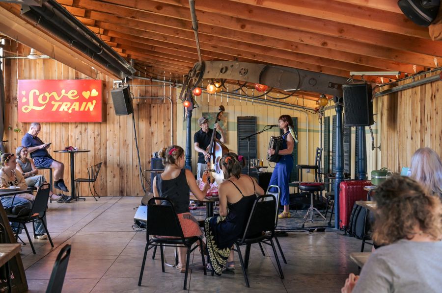 covered outdoor patio with stage and a band singing and playing accordion and upright bass for people seated at tables