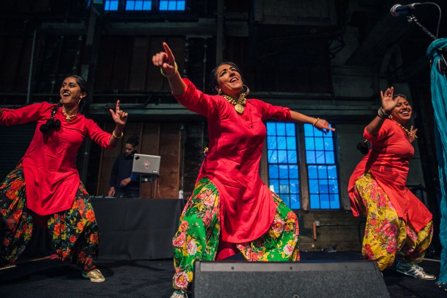 three dancers in bright clothing perform at My People's Market