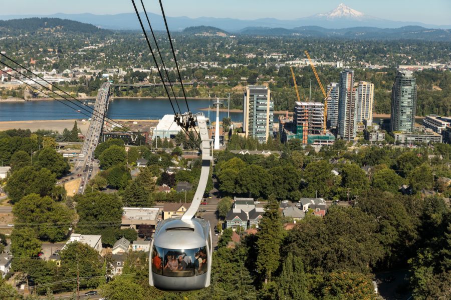 aerial tram heads up to terminal in West Hills with view looking over Willamette River and Mount Hood and the cascades