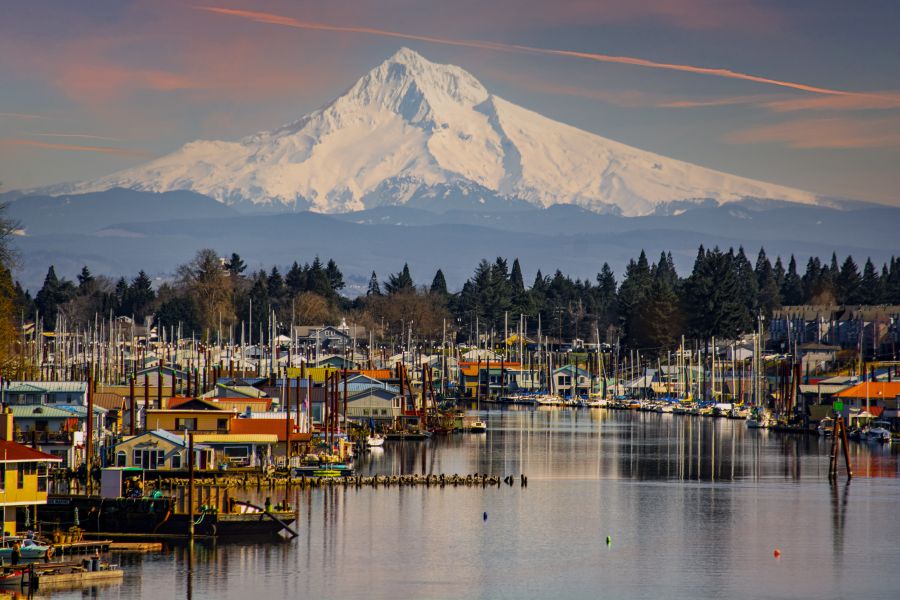 colorful boathouses sit atop the still water beneath the towering white-capped mountain