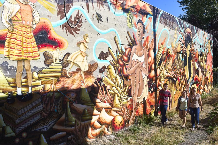 people walk in an alley off Alberta Street to see the large mural