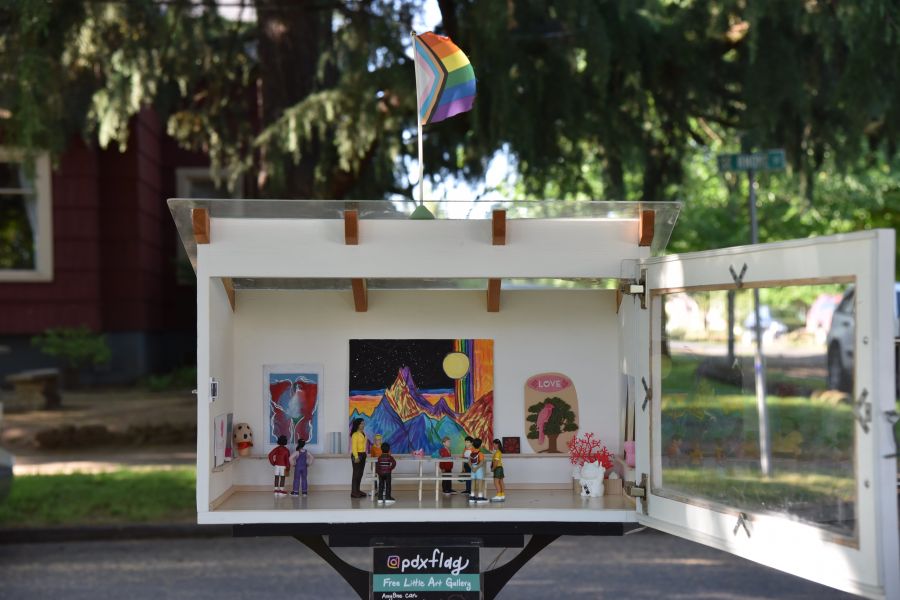 small white box with tiny art gallery diorama is displayed on a neighborhood street