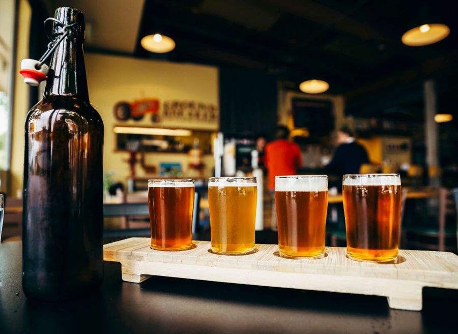 a tasting flight of draft beers next to an open bottle