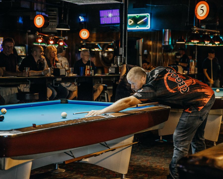 a man shoots pool in a dark bar