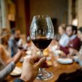 a wine glass with red wine being held up in a toast