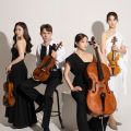 Members for the Esme Quartet dressed in black and white, posing with their instruments in a photography studio in front of a white background.