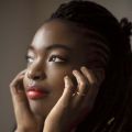 Close up of Axelle Fanyo with her head resting in her hands looking away.