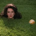 a woman's head is on a grassy lawn next to a croquet ball