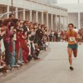a man running a marathon with a crowd watching on the sidelines