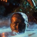 a person emerges from water with mud covering their head