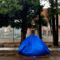 a tent covered by a tarp next to a sidewalk